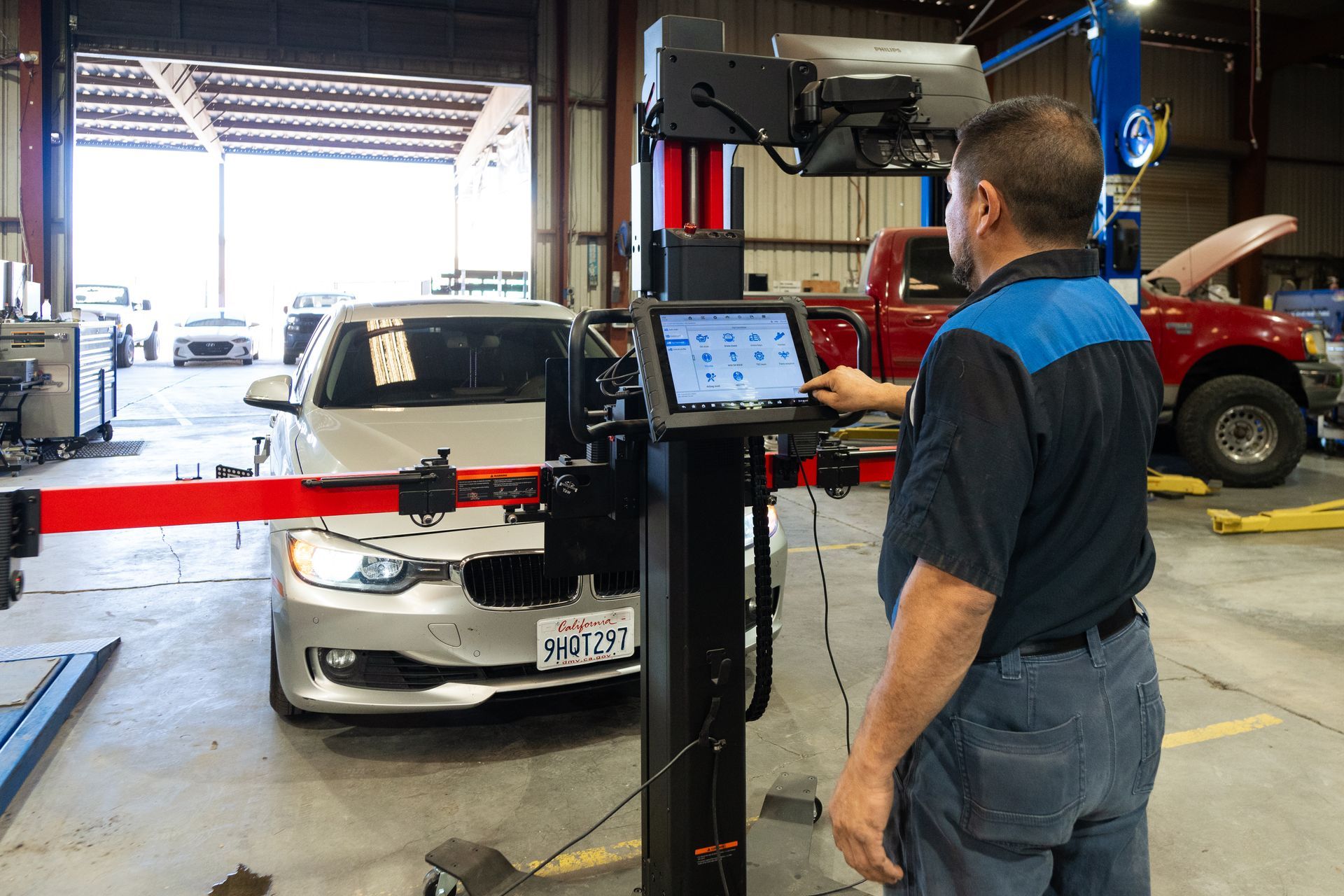 Mechanic using an alignment machine on a car in a repair shop.