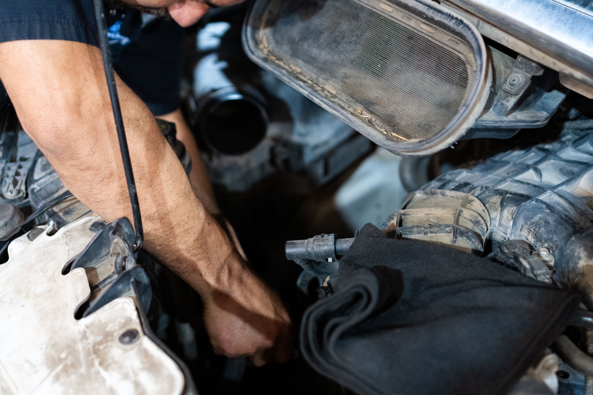 Person working on a car engine, reaching in to make a repair.