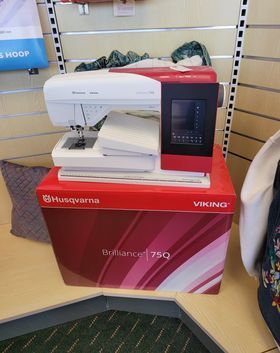 White-and-red Husqvarna Viking sewing machine display on a store counter.