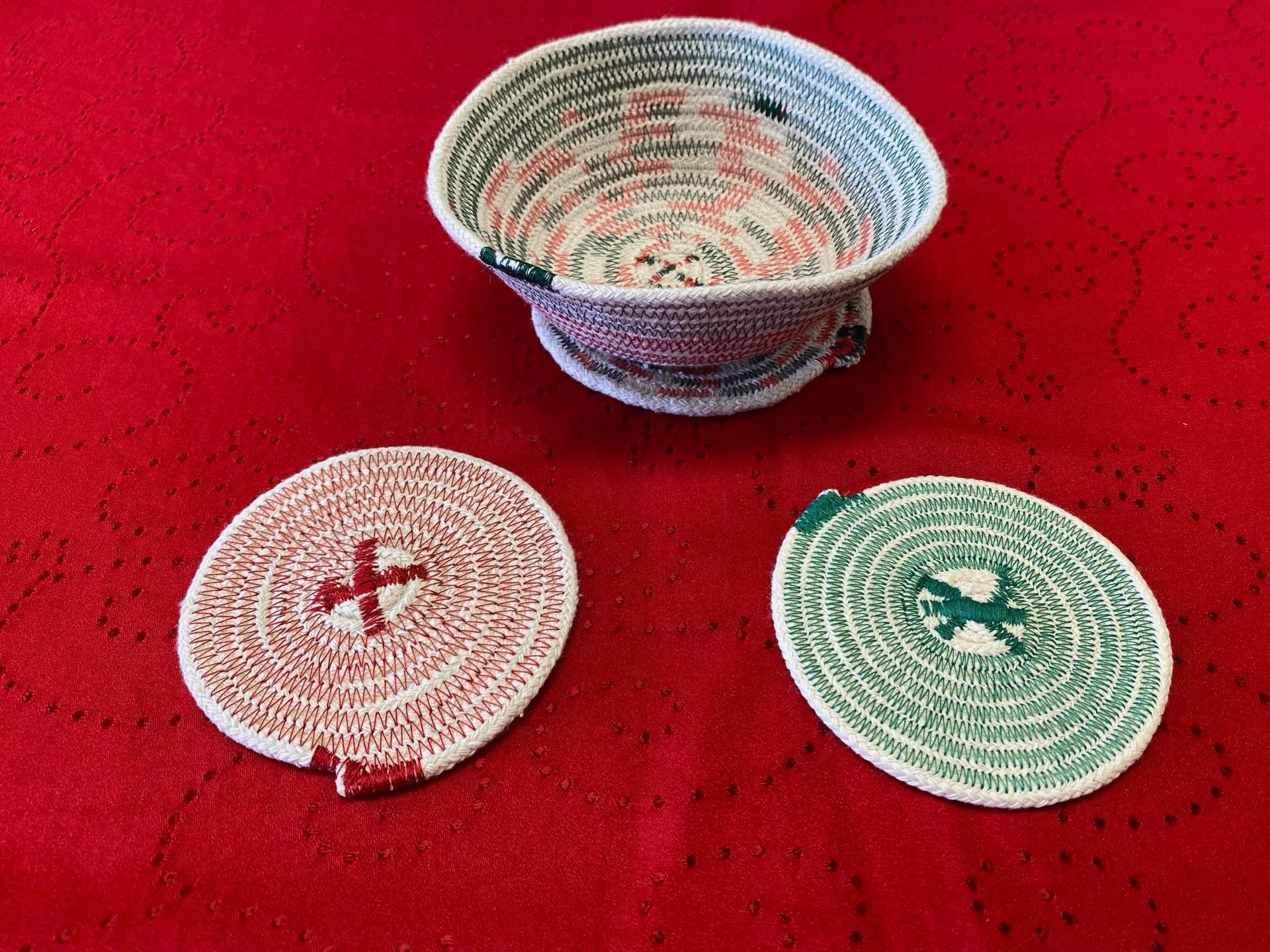 Three woven baskets on red fabric, including a larger bowl and two small round coiled baskets.
