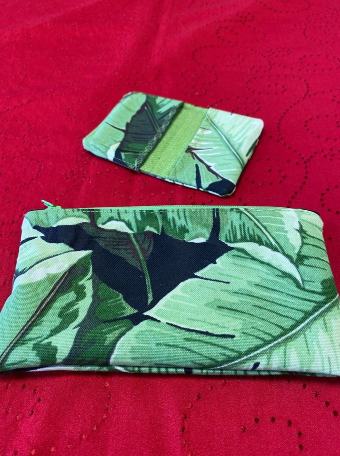 Green leaf-patterned wallet and small matching card holder on a red fabric surface