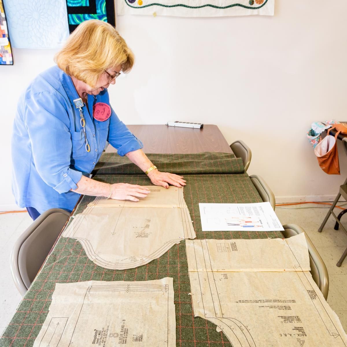 Person arranging sewing patterns on a cutting table in a bright sewing room
