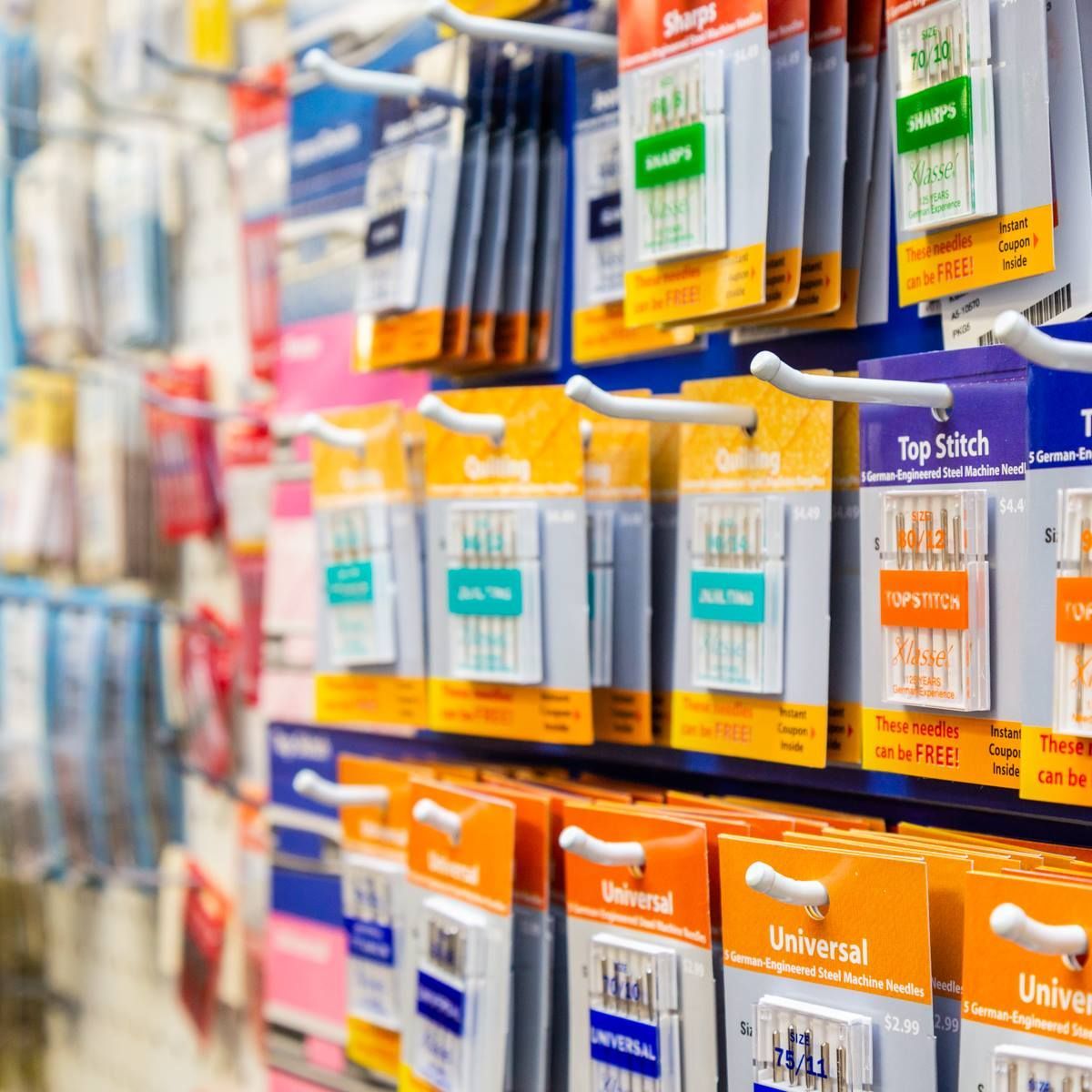 Rows of colorful sewing machine needles and accessories on a store shelf