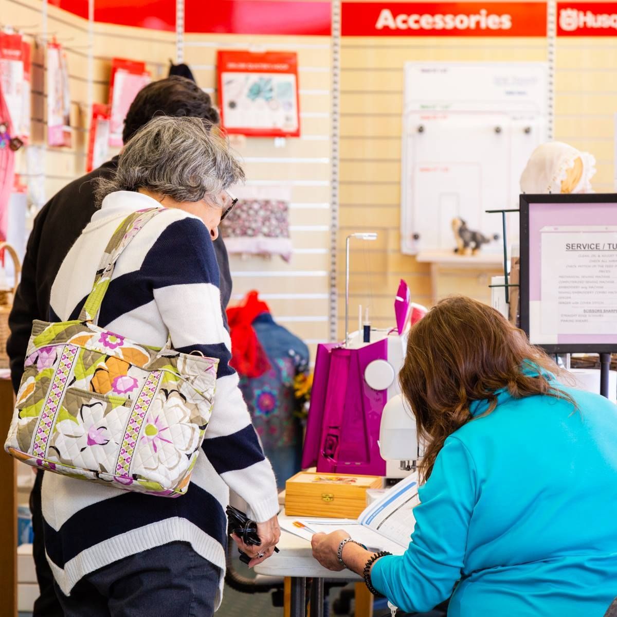 Shoppers at a retail counter in an accessories store, browsing items and completing a purchase.