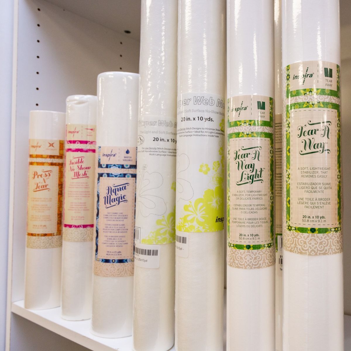 White decorative candles and bottles with colorful labels lined up on a shelf