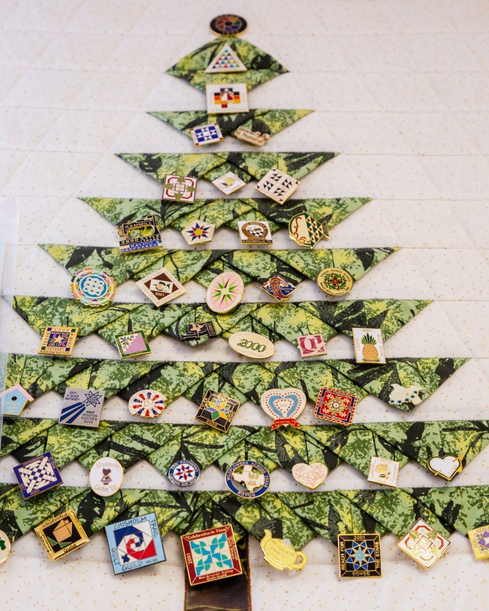 Decorative Christmas tree made of green paper triangles, covered in many small ornaments and craft decorations.