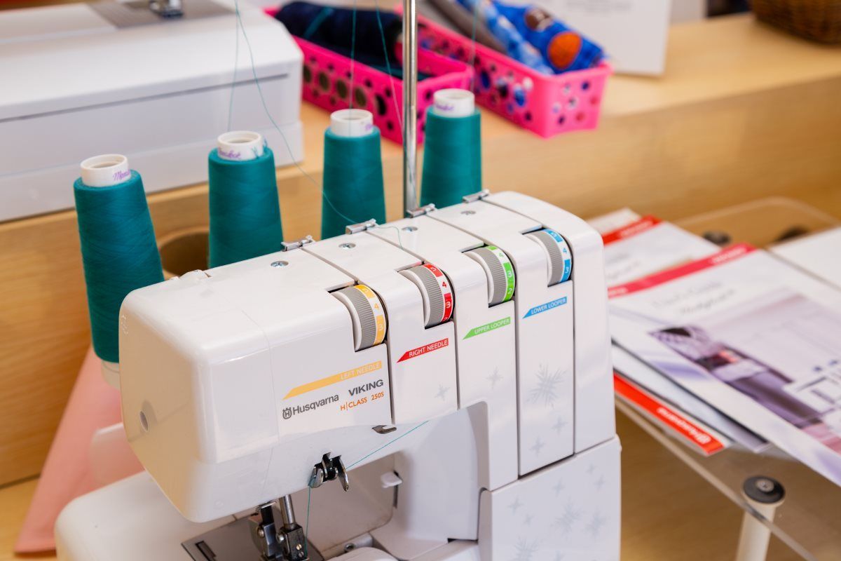 Serger sewing machine with teal thread spools on a craft table