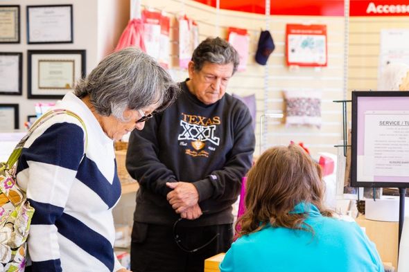 Two people talking at a customer service desk in a store or office lobby