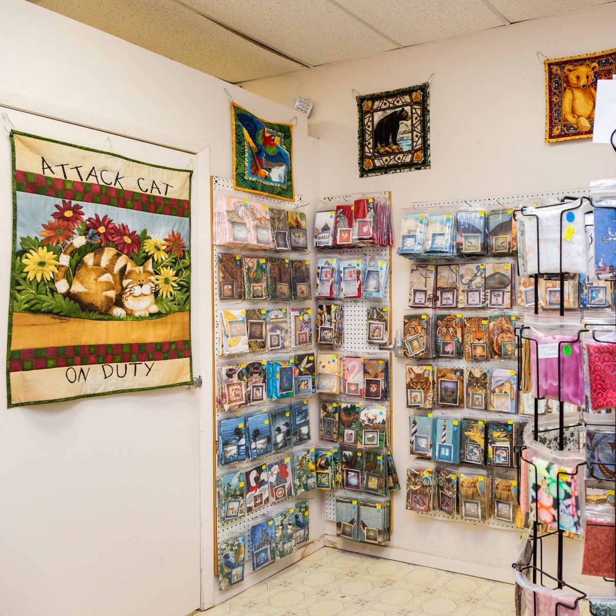 Craft room wall with organized craft supplies and framed art prints displayed on shelves and hooks.