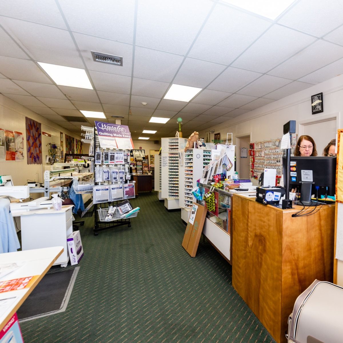 Small retail store interior with counters, shelves, and a cashier desk in the foreground