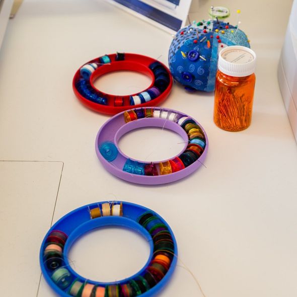 Colorful beaded bracelets beside an orange pill bottle on a white tabletop