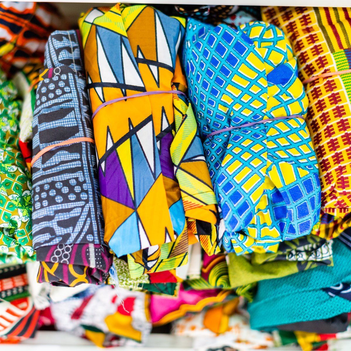 Colorful folded patterned fabrics stacked in a market display