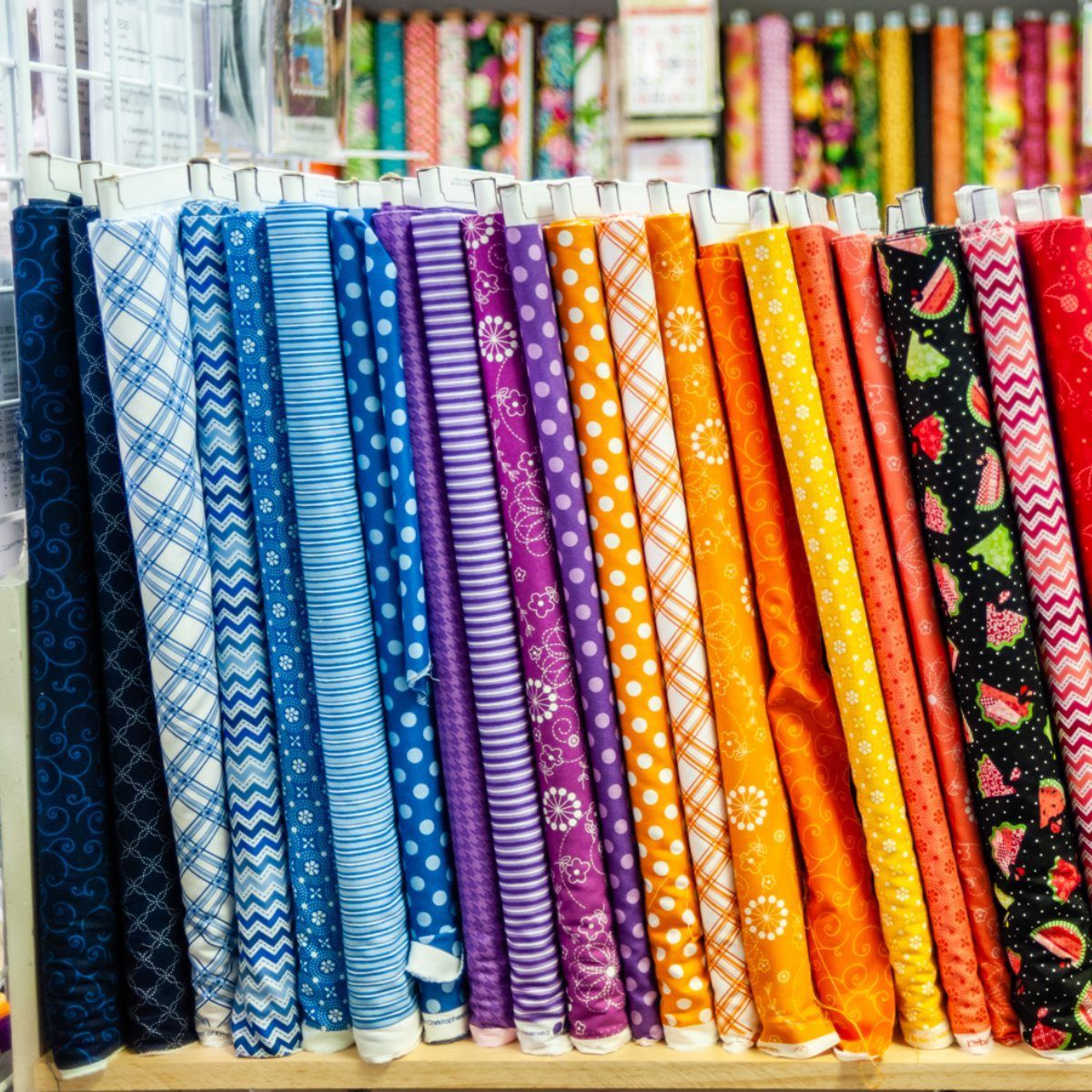 Rows of colorful patterned fabric bolts displayed in a shop