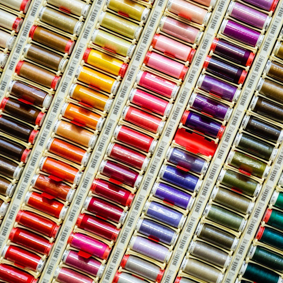 Rows of colorful thread spools arranged diagonally in a neat, patterned display
