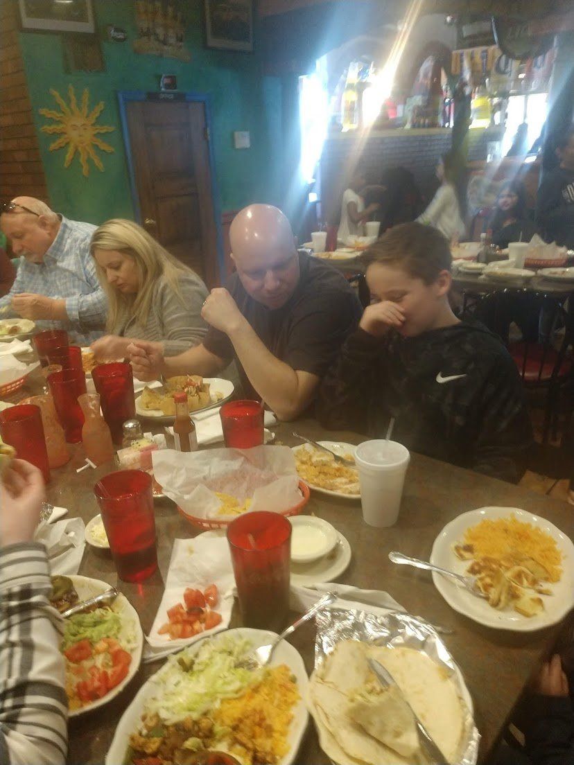 People eating at a Mexican restaurant. Table with food and drinks; family members.
