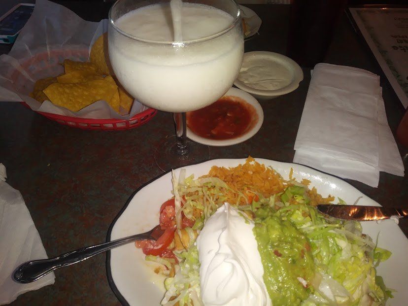 Mexican food: plate with salad, salsa, chips, and a white drink in a wine glass.