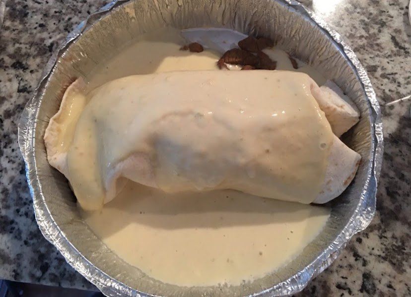 Baked chicken breast in creamy sauce, inside foil pan.
