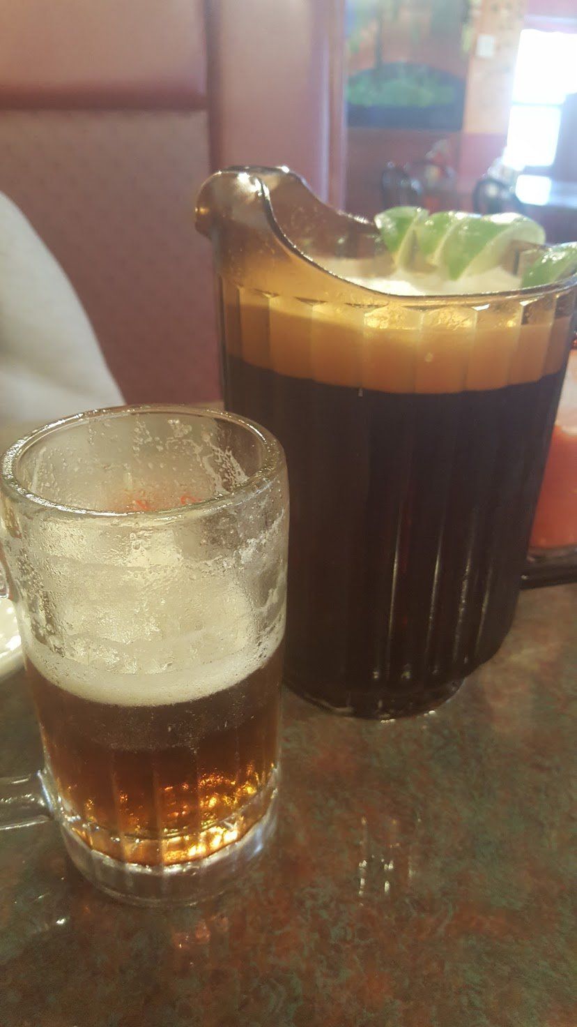 Glass of beer and pitcher of iced tea on a restaurant table.