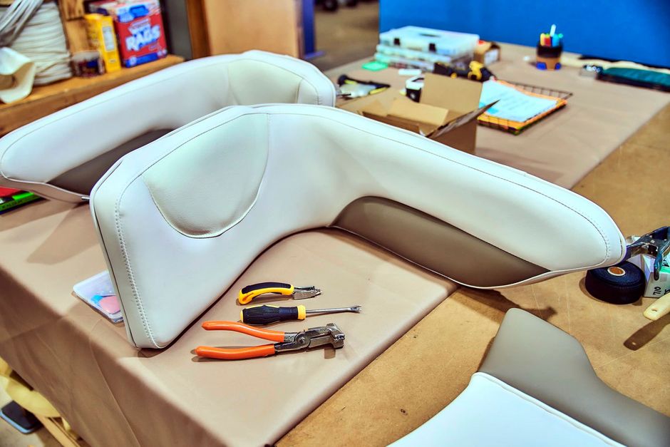 Upholstered boat seats with tools laid out on a workbench.