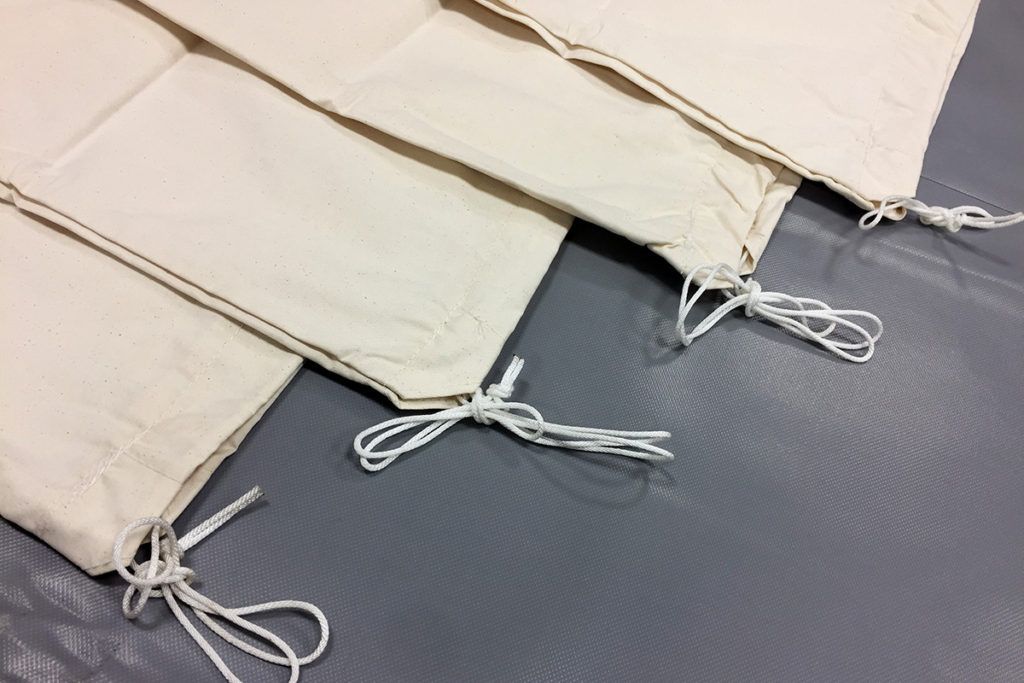 Beige fabric pieces with tied drawstrings on a gray surface.