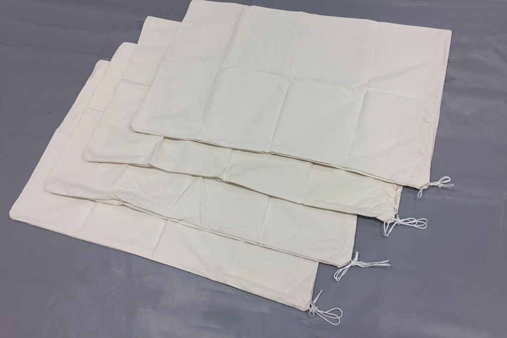 Four off-white square fabric bags, stacked, with drawstrings visible on the sides.