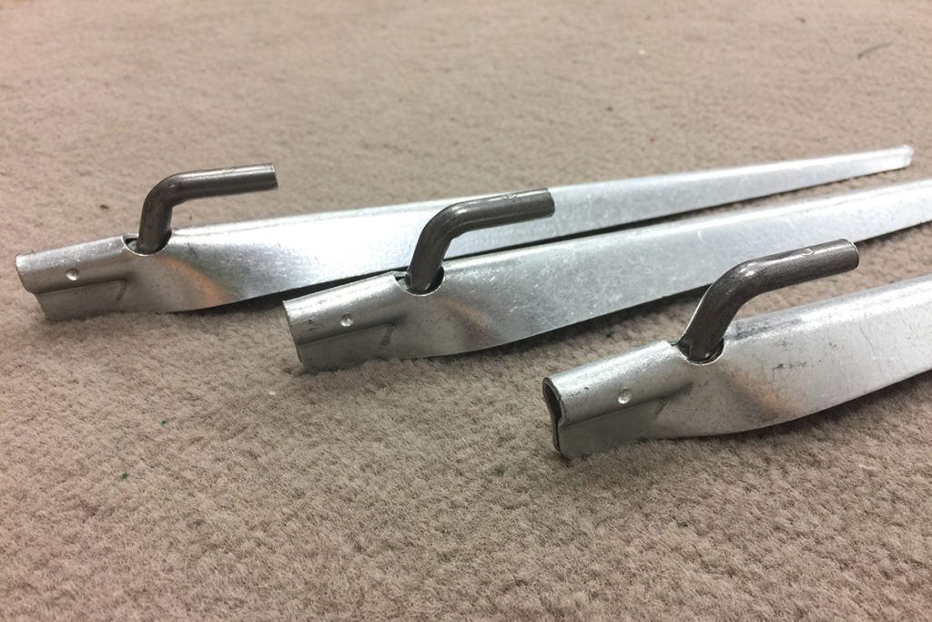 Three metal tools with angled handles resting on a carpeted surface.