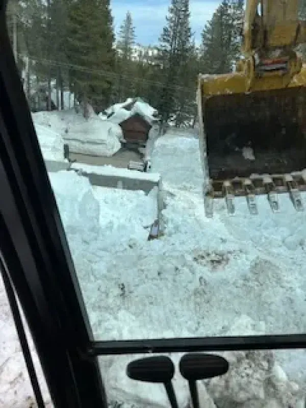 A bulldozer is clearing snow from a driveway.