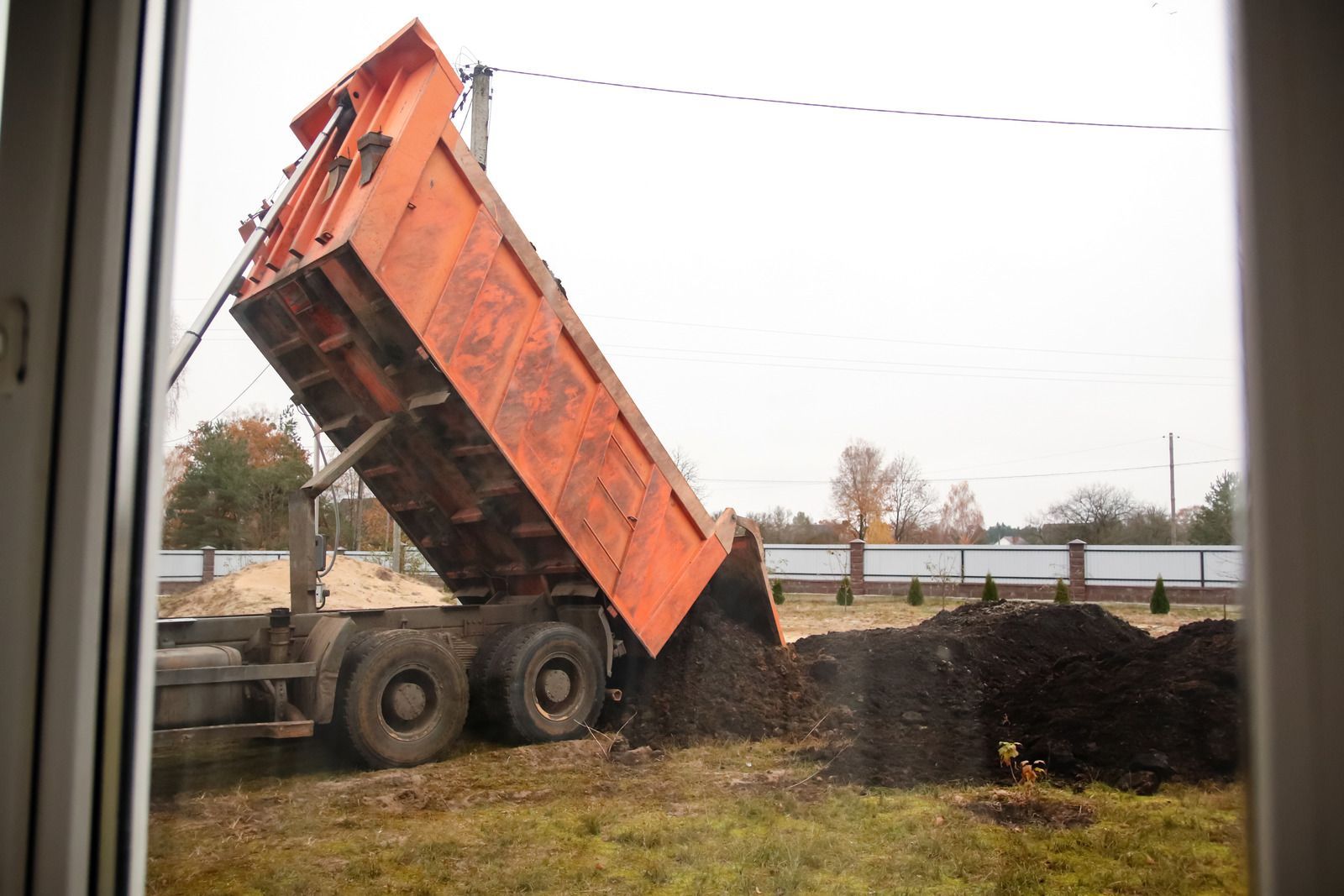 A dump truck is dumping dirt into a hole in the ground.