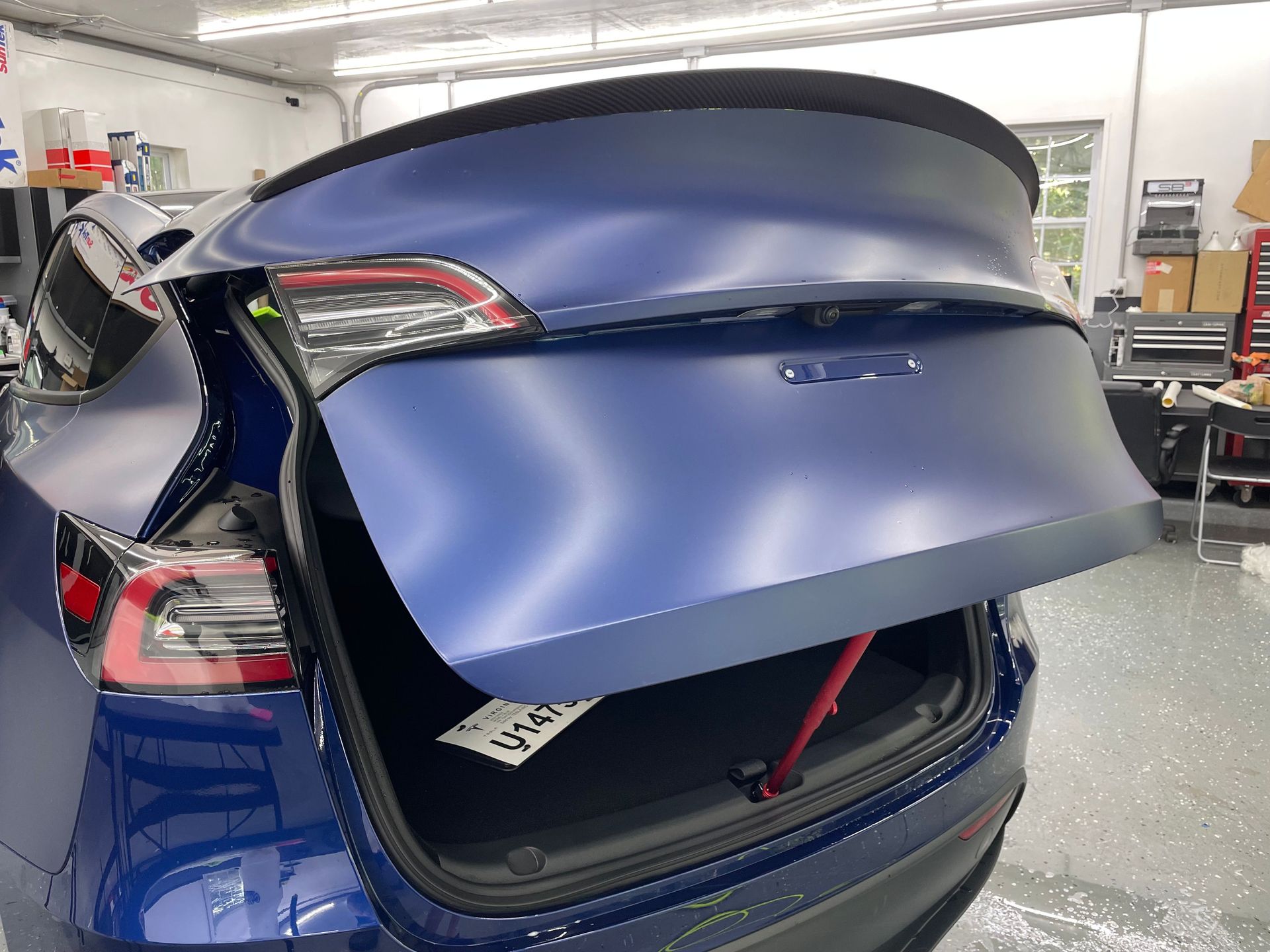 Blue Tesla car with trunk open, interior details visible.