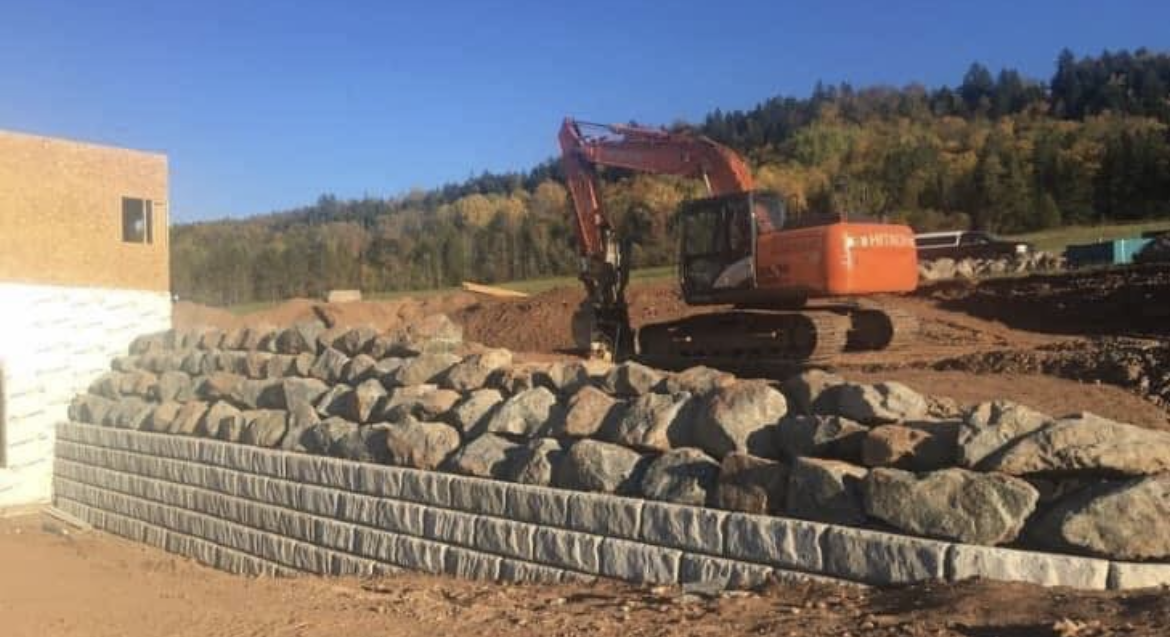 A large excavator is sitting on top of a pile of rocks.