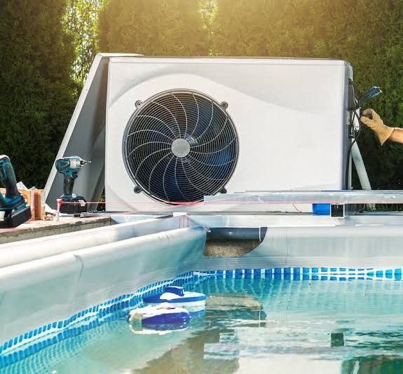 Outdoor pool with a large cooling fan unit and tools on the deck under sunlight