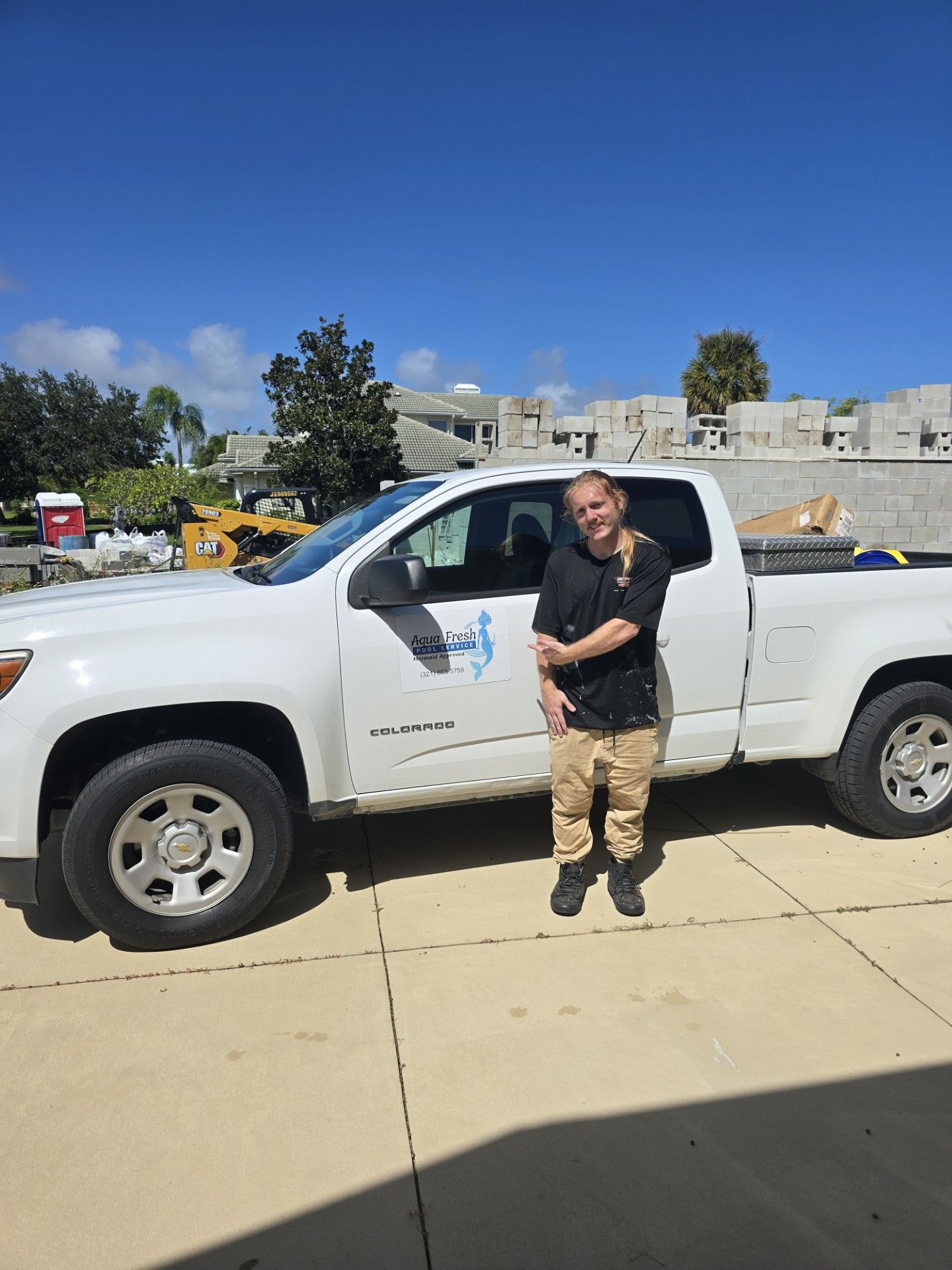 Person standing beside a white pickup truck in a sunny parking lot
