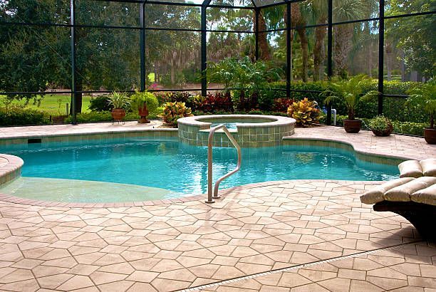 Screened backyard pool with turquoise water, stone patio, and surrounding greenery