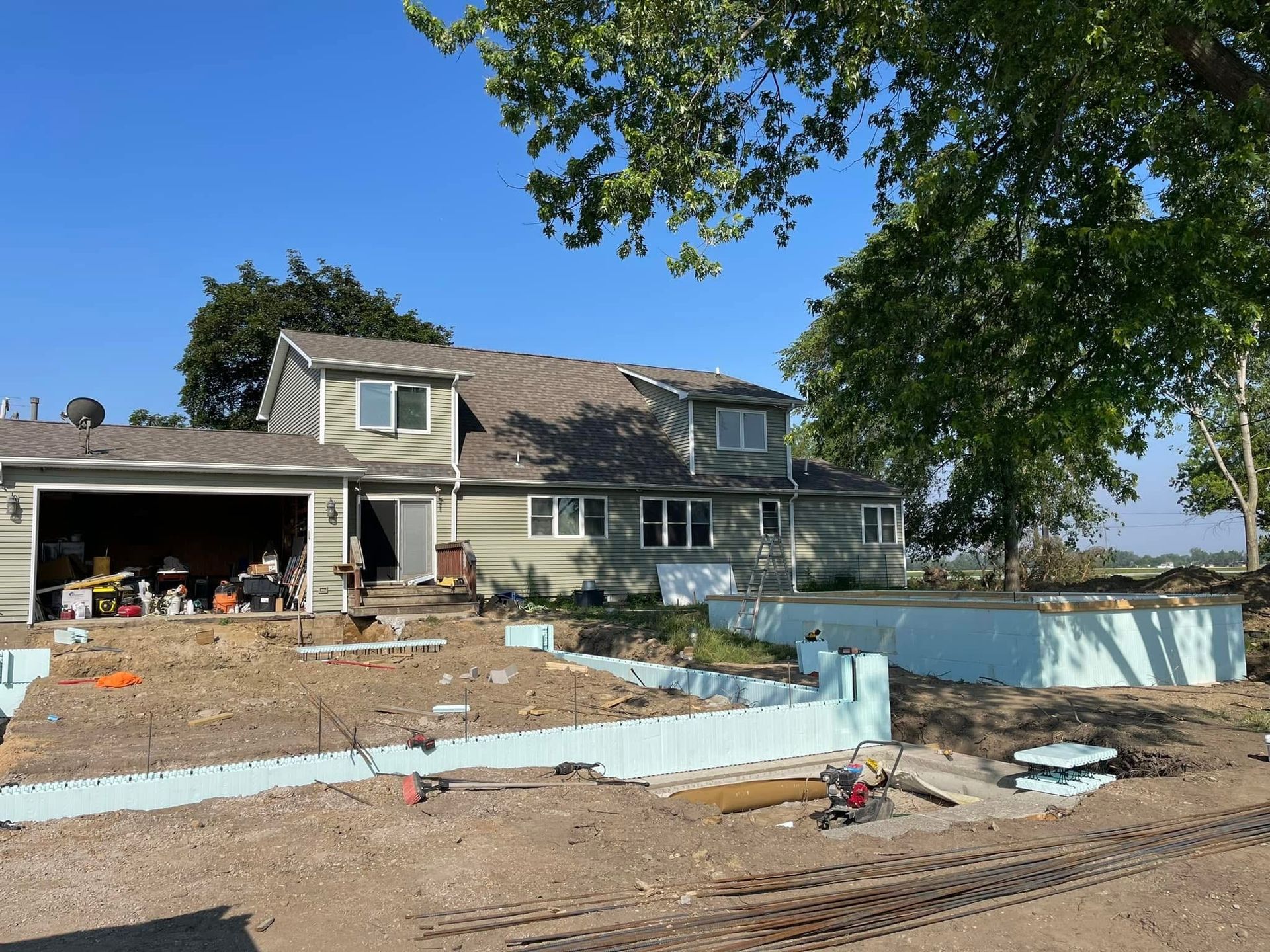 House under construction near waterfront with blue barriers and debris in the yard