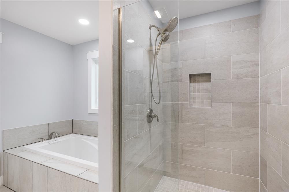 Modern bathroom with a soaking tub and glass-enclosed shower in light gray tile