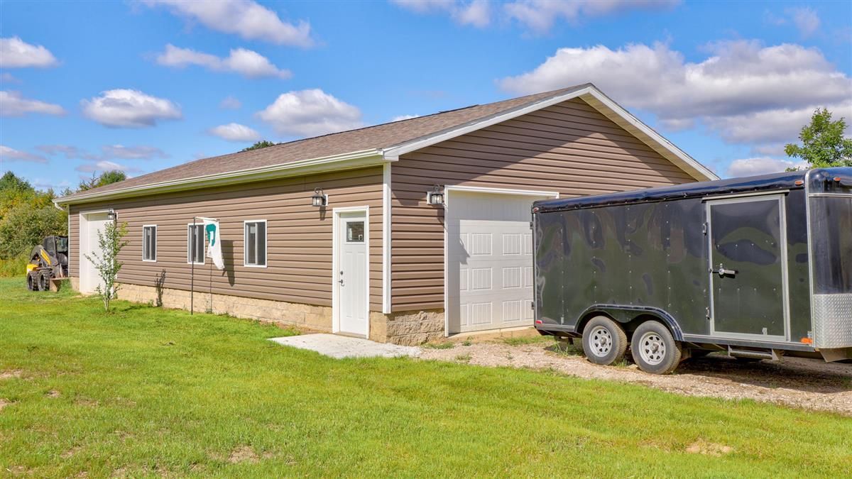 Single-story beige house with white trim and a black enclosed trailer parked beside it.