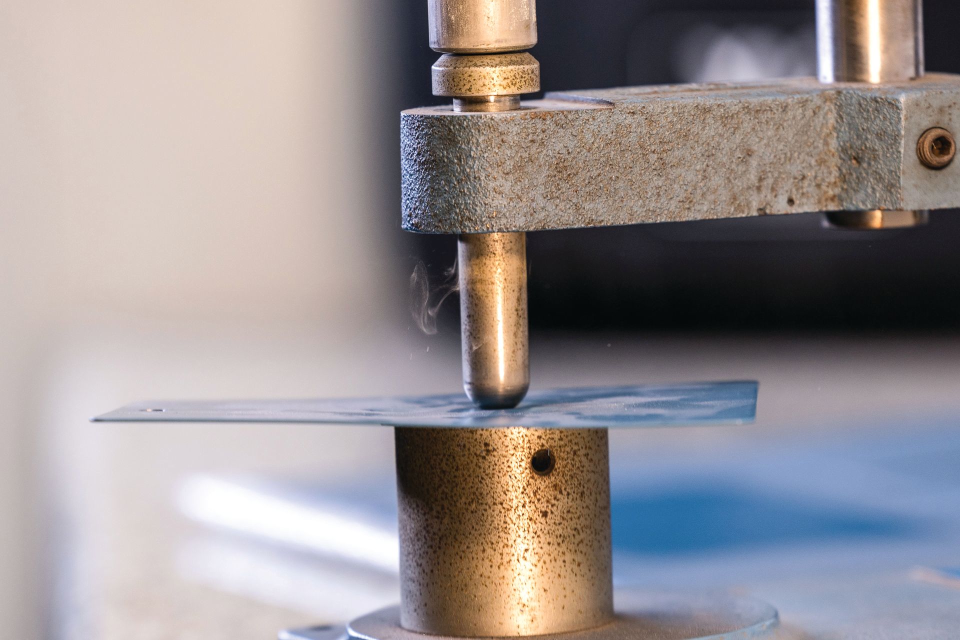 Metal testing machine pressing a thin sheet on a cylindrical base in a lab