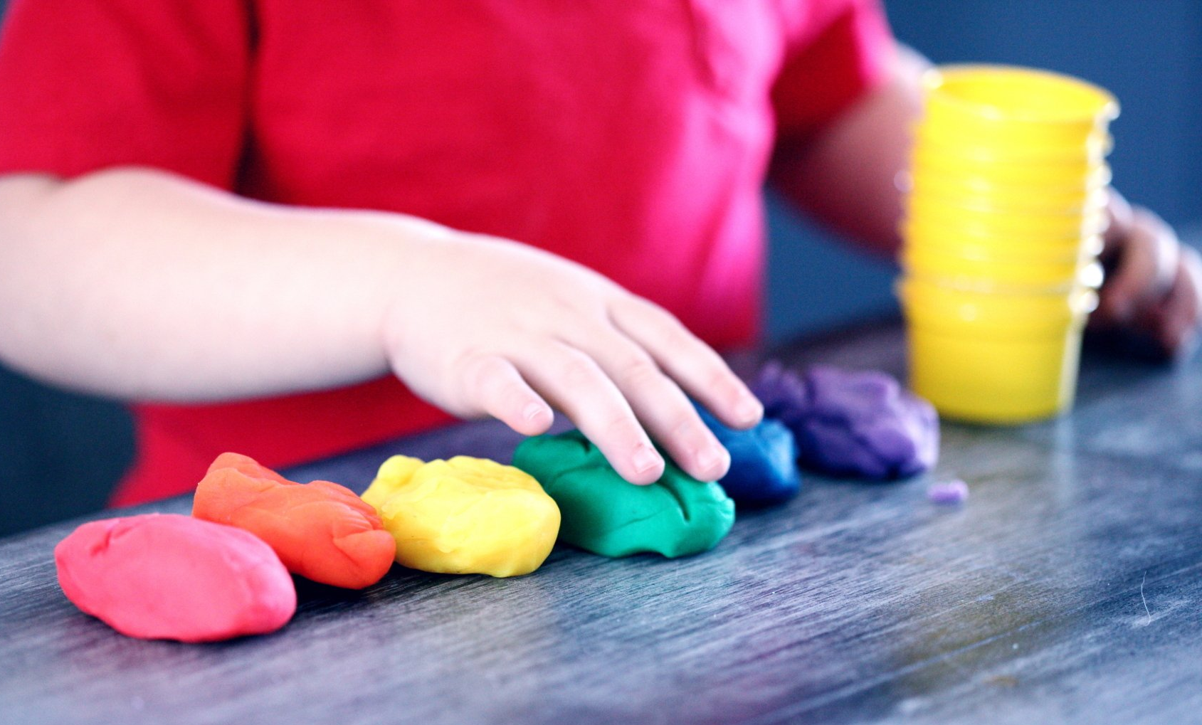 A child playing with colorful play dough, engaging in creative and hands-on play.