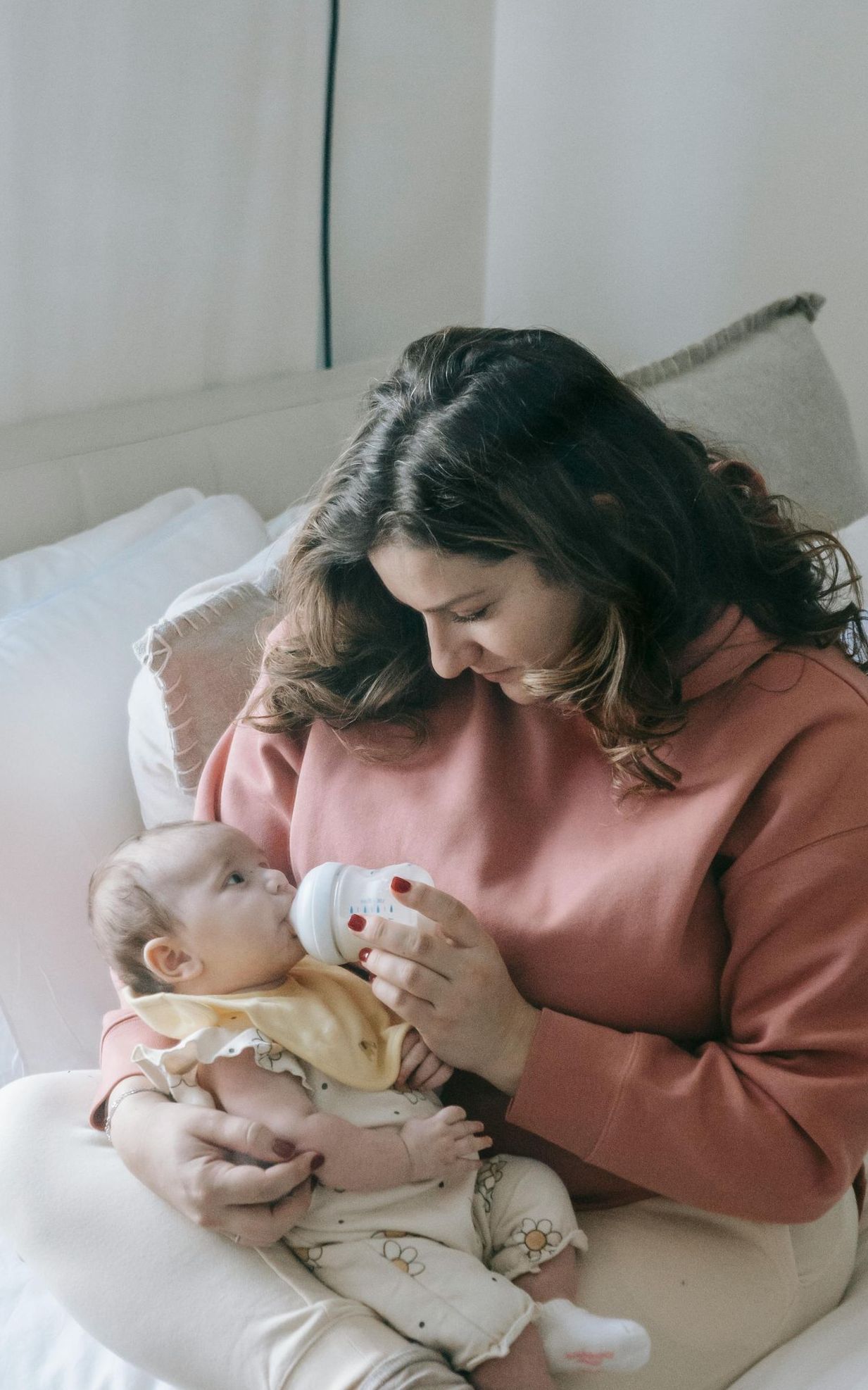 A mother feeding her baby with a bottle, providing nourishment and care in a nurturing environment.