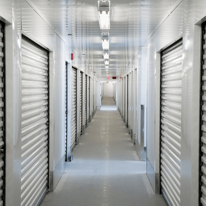 Bright white storage unit hallway with closed roll-up doors on both sides