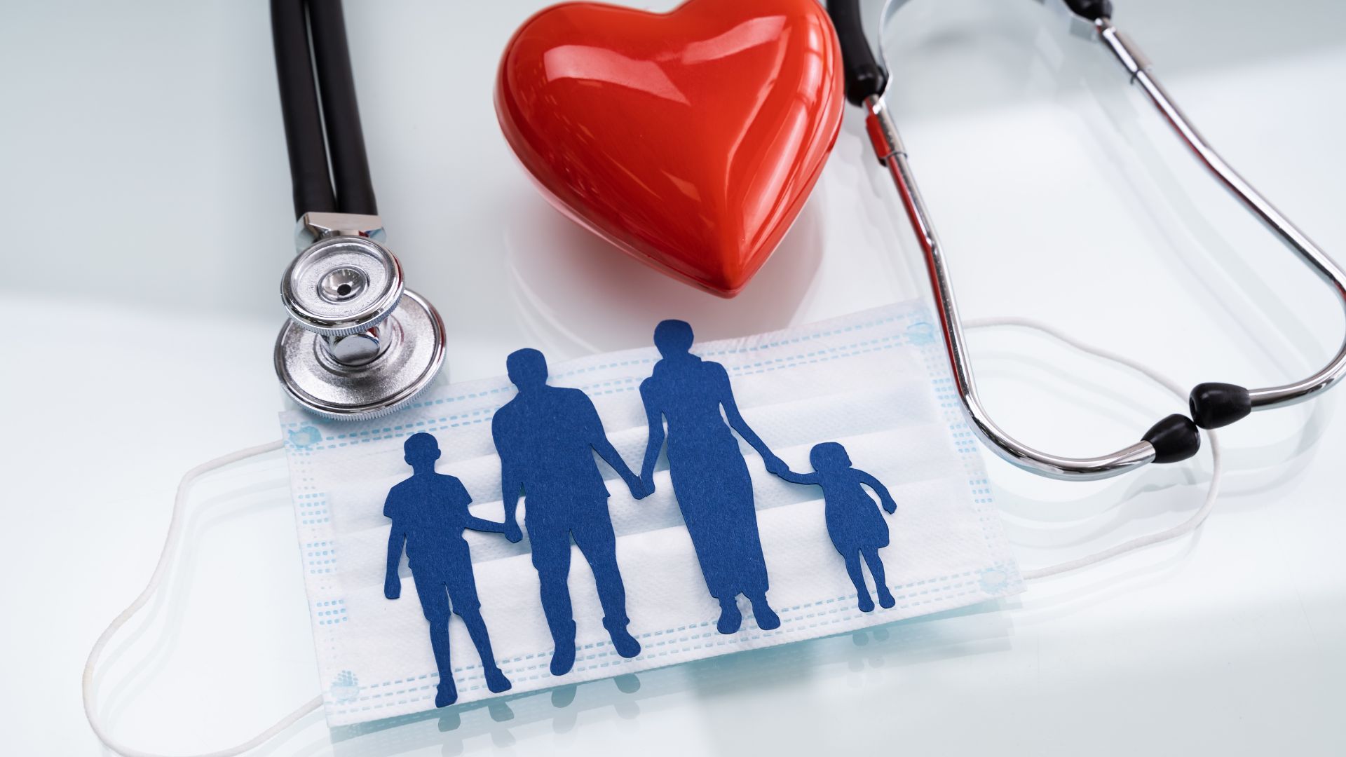 Family silhouettes beneath a red heart with a stethoscope on a medical clipboard
