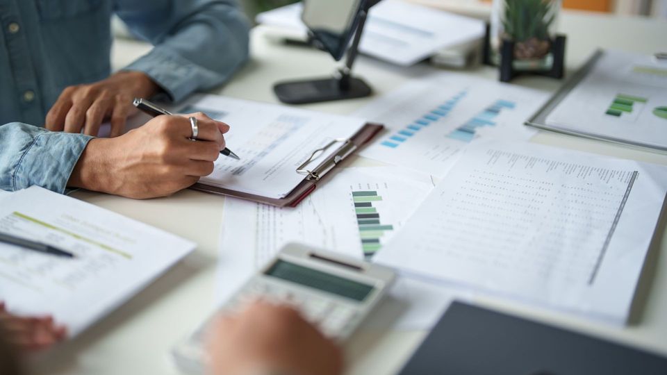 Hands reviewing charts and documents on a desk in a business meeting