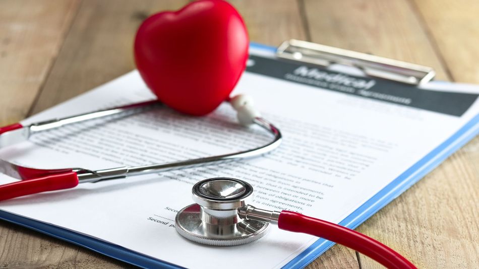 Red heart and stethoscope on a clipboard with documents, symbolizing healthcare or medical care