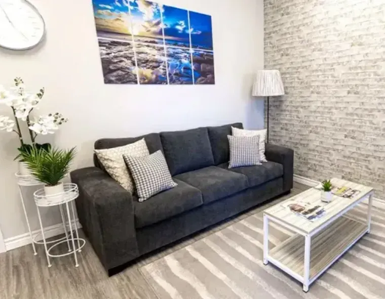 Modern living room with gray sofa, coffee table, and wall art on light wood flooring