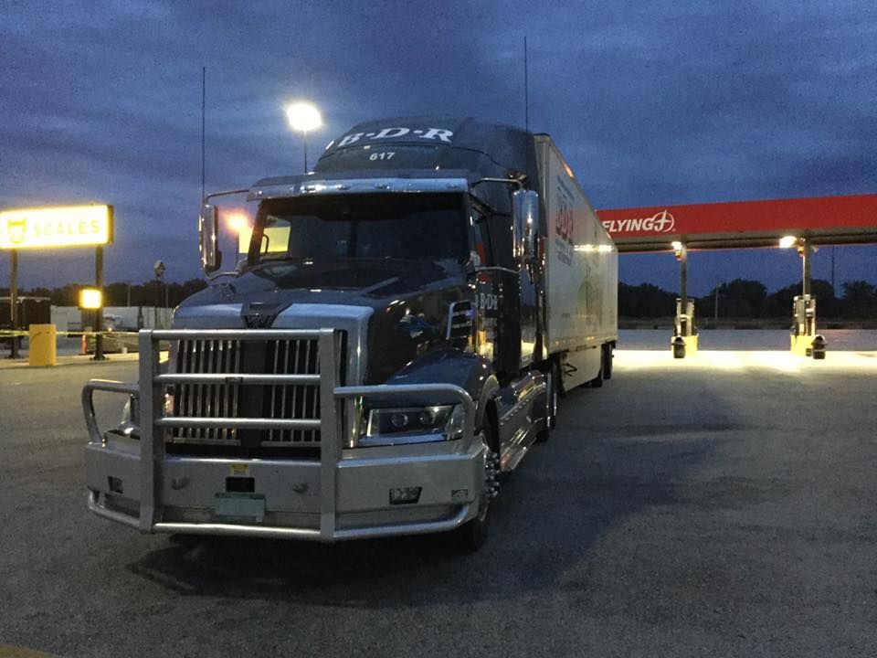 A semi truck is parked in front of a gas station