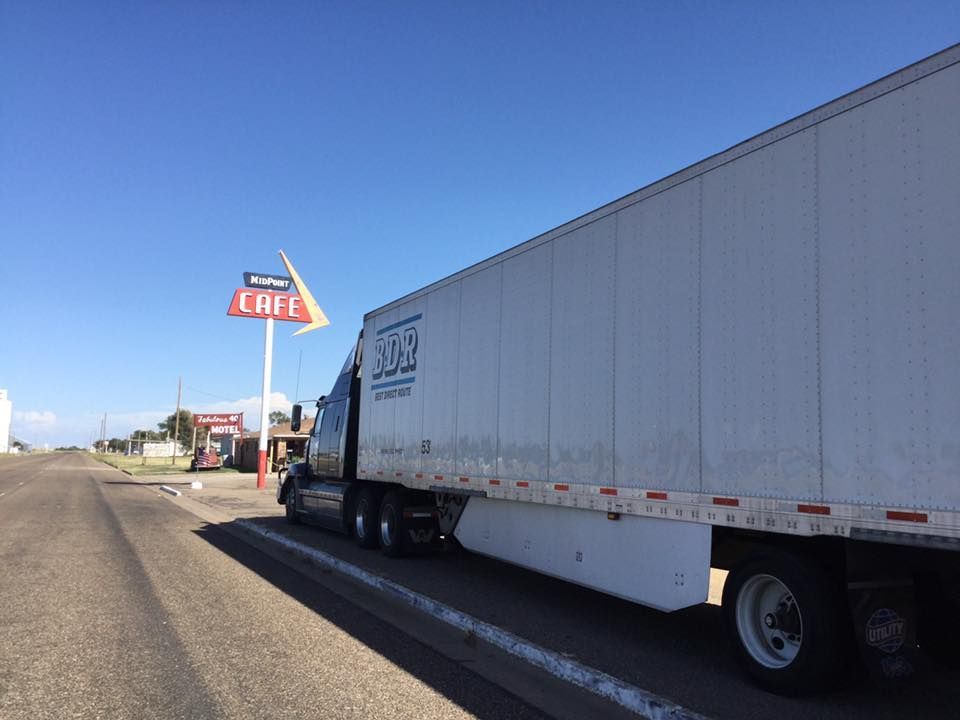 A semi truck is parked in front of a cafe sign