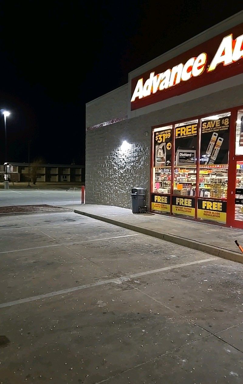 An Advance Auto Parts store at night with bright signage and illuminated windows; empty parking lot.