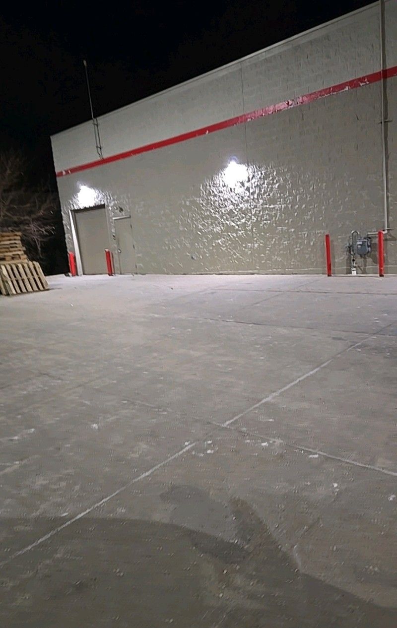Night shot of a warehouse exterior with red accents, illuminated by bright lights.