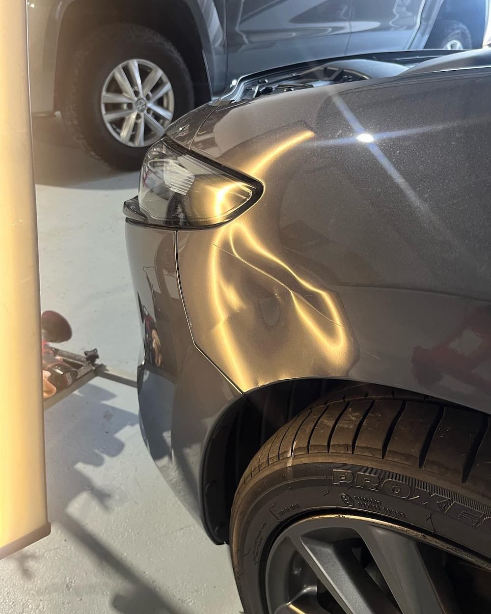 A Close-up Of a Grey Car with A Damaged Fender — Dent Motive in Southport, QLD
