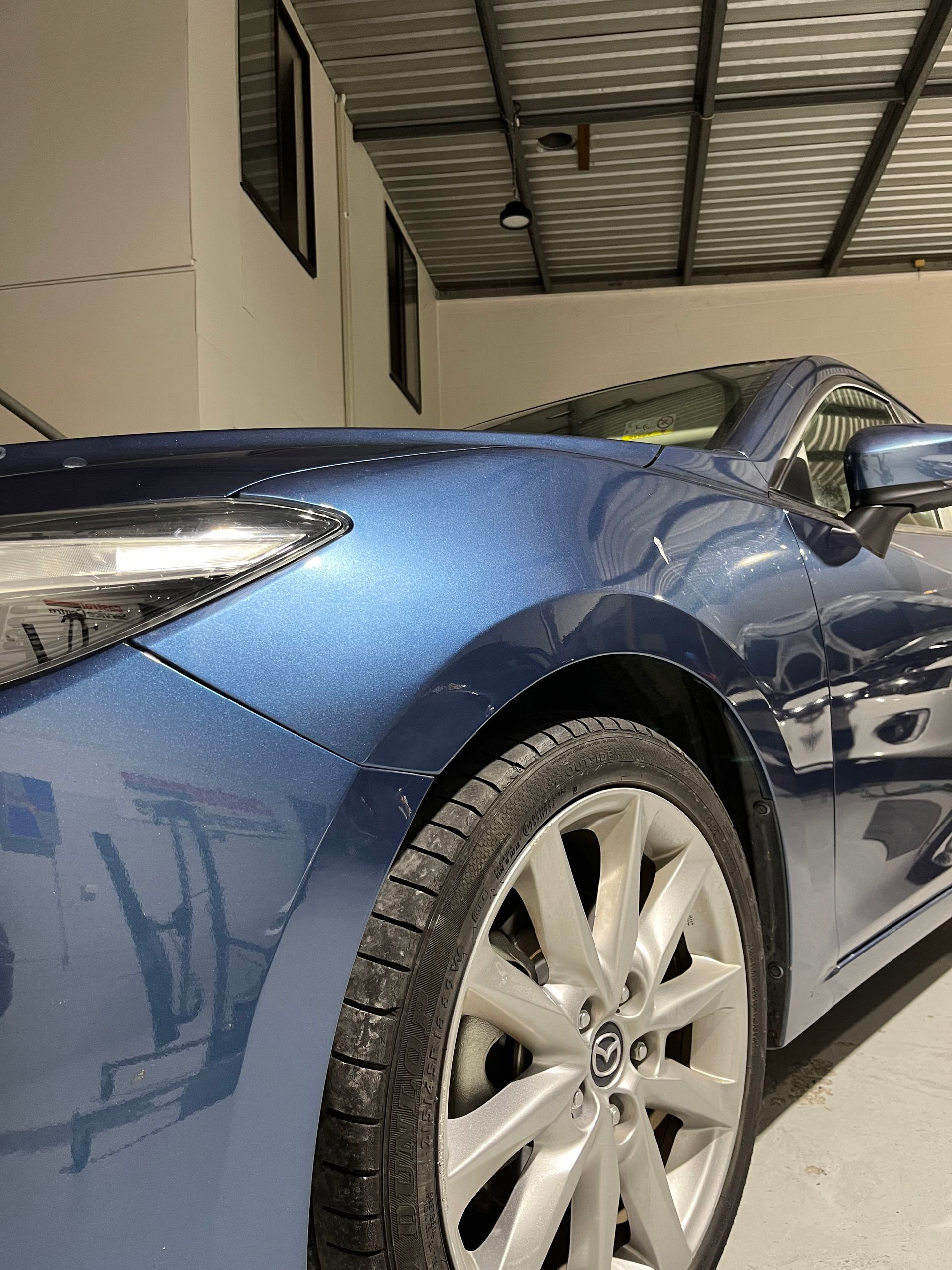 A blue sports car is parked in a garage.